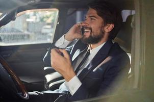 émotif homme dans une costume dans une voiture une voyage à travail Succès un service riches photo