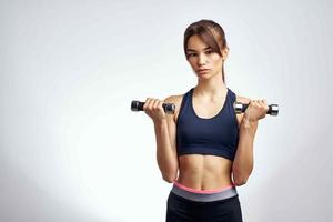 sportif femme avec haltères dans mains pompé en haut presse aptitude exercice Gym photo