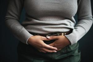 douleur de crampes dans le inférieur abdomen, femme mains sur estomac, douleur pendant menstruation génératif ai photo