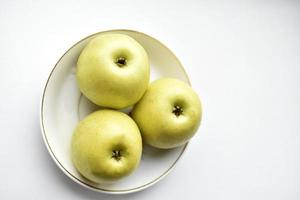 trois pommes vertes sur une assiette blanche photo