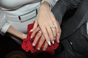mariage anneaux et bouquet de rouge des roses dans le mains de le la mariée et jeune marié photo