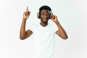 homme de africain apparence dans écouteurs écoute à la musique blanc T-shirt isolé Contexte photo