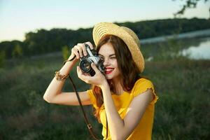 femme photographe dans chapeau à la recherche dans le caméra lentille sourire la nature loisir photo