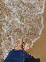 femme pieds immergé dans le mer l'eau à le plage sur une ensoleillé chaud journée photo