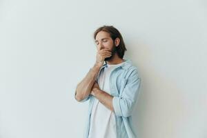 millénaire homme avec une barbe des stands contre une blanc mur et couvertures le sien visage avec le sien main de tristesse, stress photo