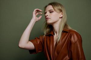 cool portrait dans studio avec élégant professionnel blond femelle modèle dans branché cuir robe. studio séance photo dans plus de olive vert Contexte