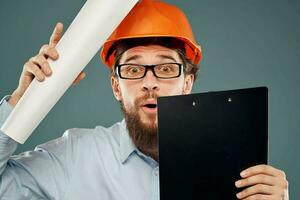 homme dans des lunettes avec les documents Orange casque sécurité travail construction photo