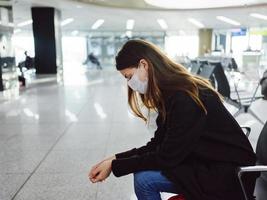 femme avec fermé yeux dans médical masque séance à le aéroport attendre pour une longue temps photo
