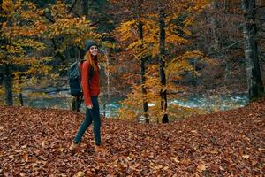 une voyageur avec une sac à dos des promenades dans le parc dans la nature près le rivière dans l'automne photo