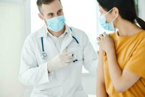 une laboratoire assistant dans une médical robe détient seringues dans le sien main et une patient convoitise vaccination photo
