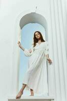 magnifique femme dans une blanc robe dans le forme de un ange dans le fenêtre ouverture photo