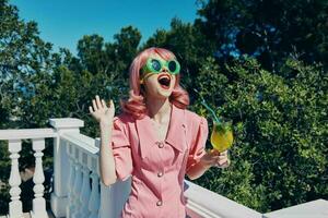 portrait de magnifique femme dans vert des lunettes de soleil avec cocktail dans été en plein air inchangé photo