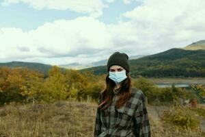 portrait de une femme dans le montagnes avec une médical masque sur sa visage photo