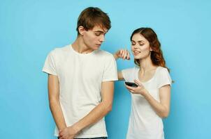 Jeune couple dans blanc t-shirts avec Téléphone (s dans mains La technologie photo