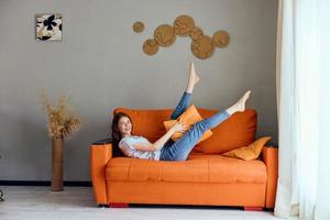 magnifique femme sur le Orange canapé dans le du repos pièce posant mode de vie photo