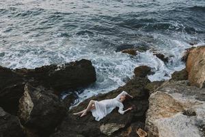 attrayant femme avec longue cheveux dans blanc mariage robe sur mer rive humide cheveux la nature paysage photo