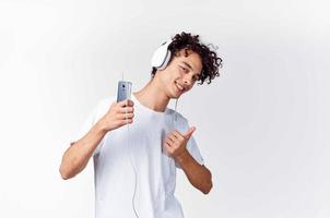 aux cheveux bouclés gars dans blanc T-shirt avec écouteurs la musique La technologie divertissement photo