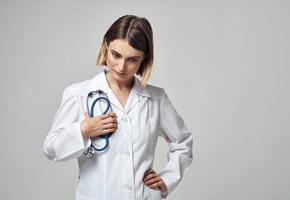 une professionnel médecin dans une médical robe détient une stéthoscope dans le sien main photo