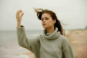 de bonne humeur femme rouge cheveux dans une chandail par le océan content femelle relaxant photo