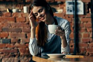 jolie femme serveur tasse avec boisson café brique mur photo
