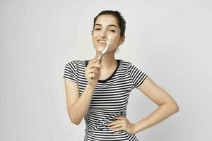 brunette dans une rayé T-shirt brosse à dents dans main isolé Contexte photo