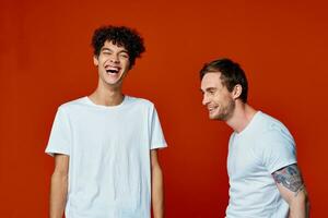 deux Hommes dans blanc t-shirts sur une rouge Contexte relation amicale photo