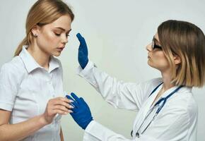 femme médecin dans une médical robe et dans bleu gants avec une stéthoscope autour sa cou et une femelle patient photo