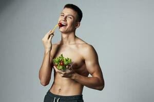 athlétique gars avec nu épaules assiette salade faire des exercices bodybuilder énergie photo