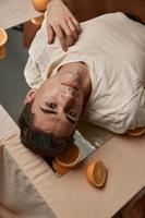 une homme mensonges sur une table sur une miroir des oranges attrayant Regardez confiance en soi modèle photo