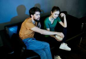 une homme et une femme sont en train de regarder une film dans le cinéma sur le canapé à l'intérieur photo