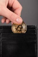 La main met une pièce de monnaie bitcoin dans le portefeuille photo