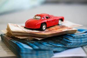 krasnodar, Russie - 4 Mars , 2021. rouge jouet voiture sur une pile de argent. russe argent roubles. assurance, crédit, prêt. photo