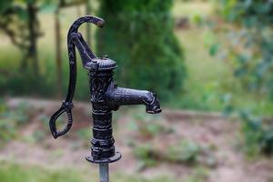 vieux ancien rétro noir pompe bien dans le jardin sur vert Contexte photo