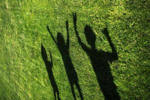 silhouette de trois personnes debout avec leurs mains tendues sur l'herbe verte photo