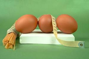 poulet Oeuf et mesure ruban sur une blanc Coaster sur une vert Contexte. régime et en bonne santé vivant concept photo