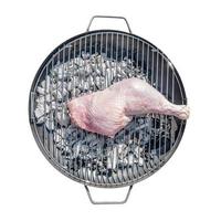 gros poulet jambe préparé pour gril à une rond barbecue poêle à feu isolé à blanc Contexte. concept de nourriture dans Extérieur cuisson. photo