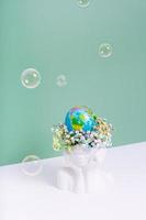 Créatif vase dans le forme de une tête avec fleurs et une monde globe avec savon bulles. enregistrer le planète, Terre journée concept photo