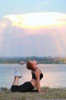 Jeune fille Faire yoga aptitude exercice Matin lever du soleil Extérieur dans le Prairie magnifique montagnes paysage. méditation et se détendre. photo