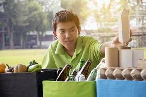 Jeune asiatique garçon en portant des boites de nourriture et séparer autre ordures dans le parc, environnement se soucier concept. photo