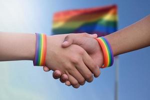 fermer vue de poignée de main de lgbt gens avec flou arc en ciel arrière-plan, concept pour succès, coopération, réconciliation, confiance, et l'amour pour lgbt gens et célébrations dans fierté mois. photo