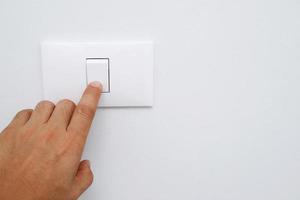 éteignez la lumière, la main de l'homme en gros plan ferme l'interrupteur d'alimentation avec le mur à la maison pour économiser de l'énergie. réduire le réchauffement climatique. photo