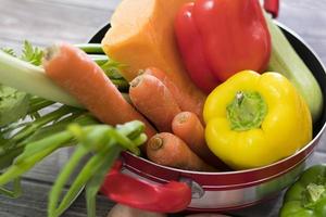 Bouchent les légumes frais pour la soupe dans un pot rouge photo