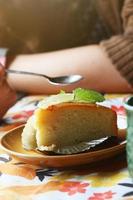 femme main en portant avec cuillère pour citron dessert gâteau et menthe feuille sur Haut gâteau dans boulangerie et café magasin photo