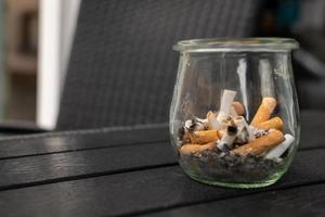 verre avec vieux cigarettes sur une table photo