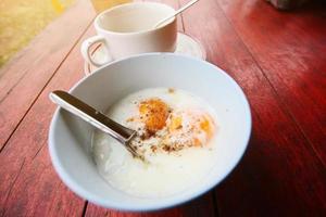 chaud café avec riz bouillie, Oeuf et porc sur blanc bol sur bois tableau. petit déjeuner dans Thaïlande photo