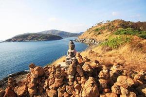 magnifique pyramide forme de des pierres arrangé avec Bouddha statue dans Zen sur Roche Montagne dans paysage marin de le coucher du soleil et mer horizon avec sec herbe champ sur phrom thep cap dans phuket île, Thaïlande. photo