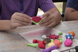 un autistique garçon moulage différent formes de coloré pâte à modeler préparé par Parents à Accueil dans commande à développer divers aspects dans leur fils lequel a Ralentissez cerveau développement que Ordinaire les enfants. photo