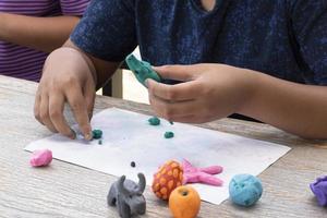 un autistique garçon moulage différent formes de coloré pâte à modeler préparé par Parents à Accueil dans commande à développer divers aspects dans leur fils lequel a Ralentissez cerveau développement que Ordinaire les enfants. photo