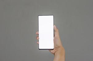 femme en portant téléphone intelligent avec blanc écran sur gris Contexte photo