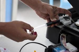 le technicien répare l'imprimante. en aspirant la peinture pour chasser les bulles. photo